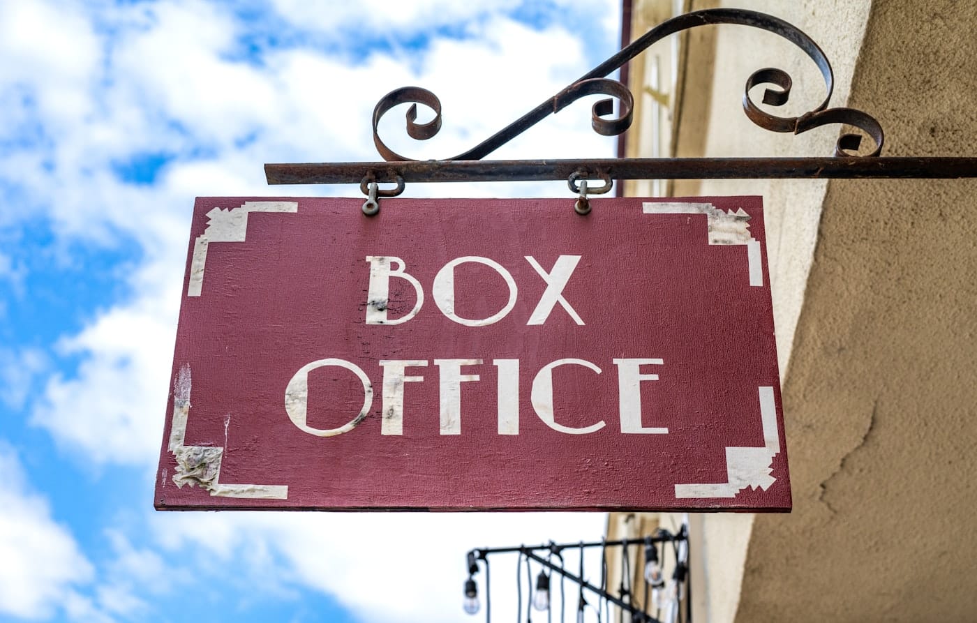 a red box office sign hanging from the side of a building