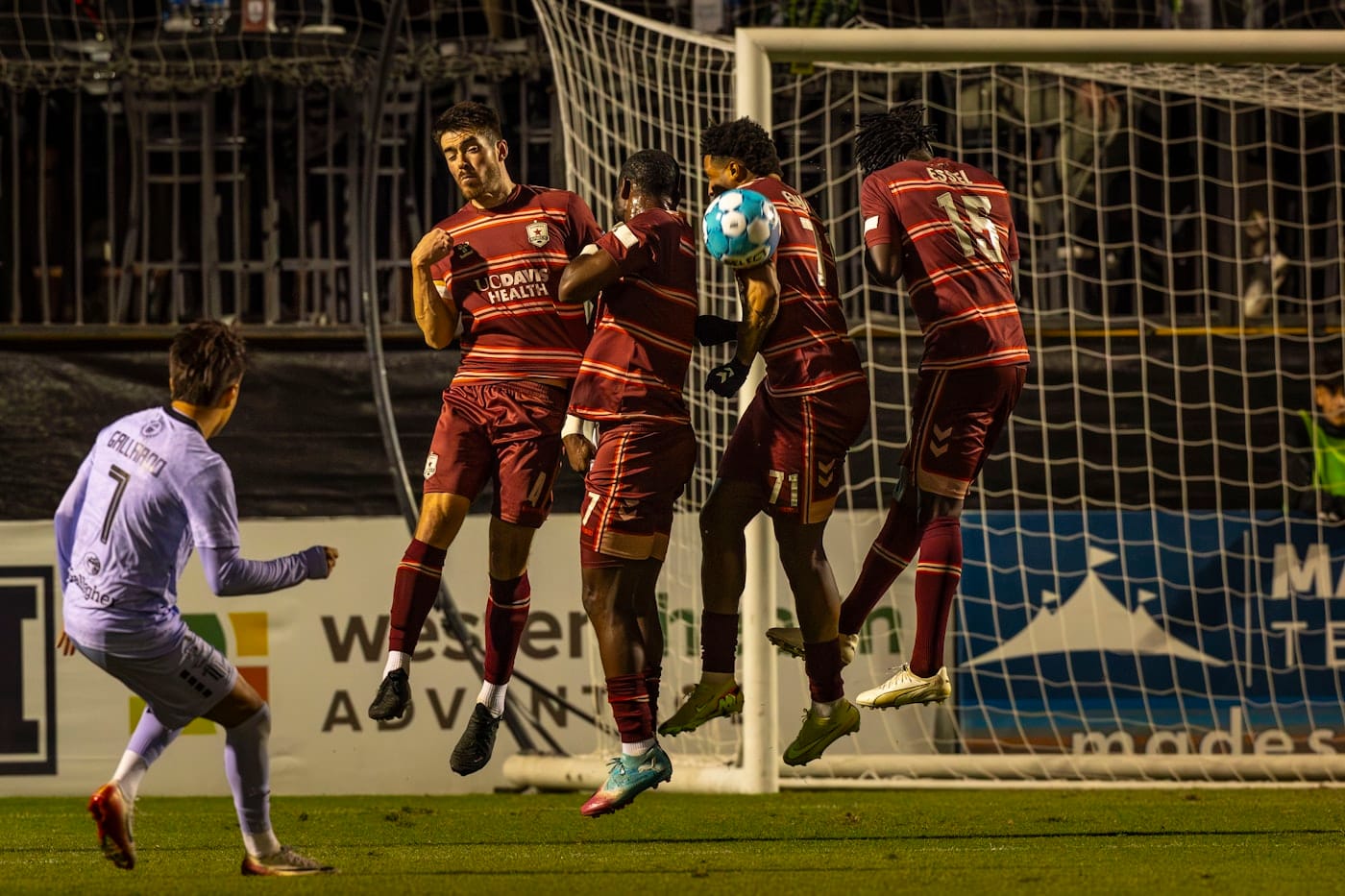 Soccer players jumping to head the ball near goal