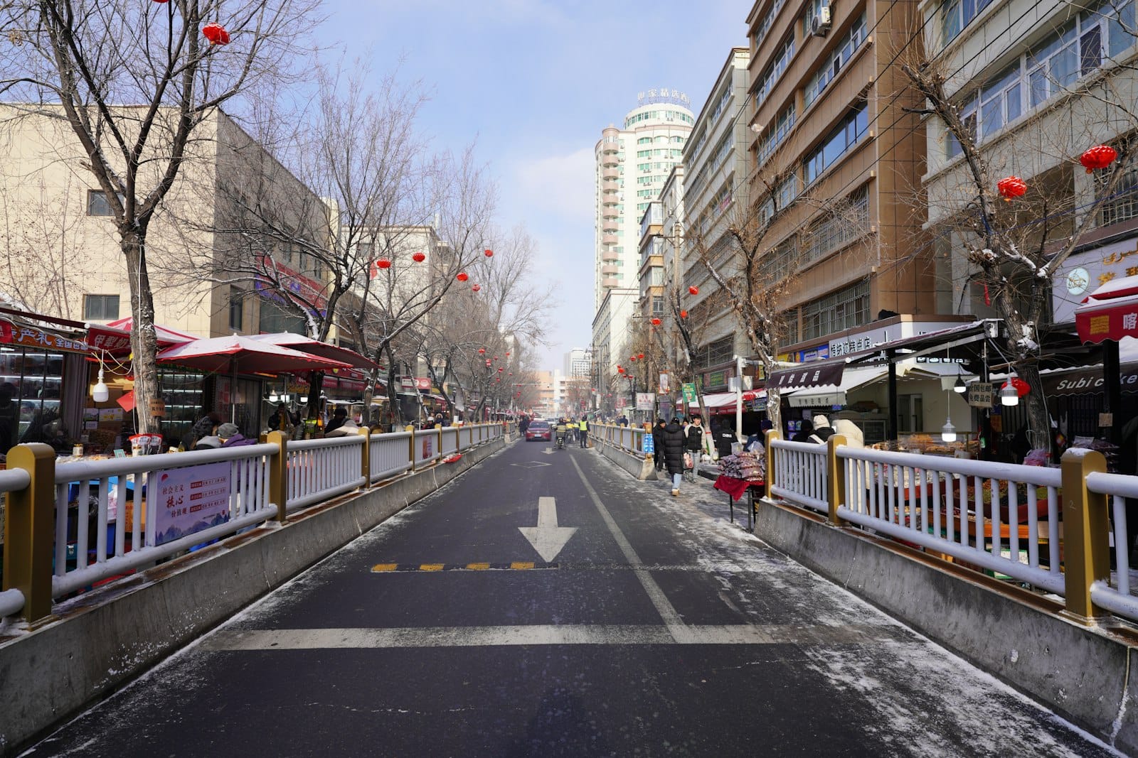 Snowy street with buildings and bare trees