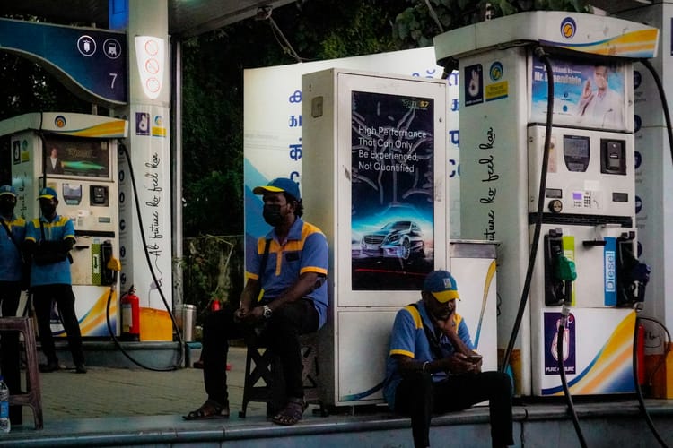 Gas station attendants sit near pumps